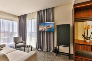a hotel room with a couch and a tv at Hotel Kalos by Aycon in Budva
