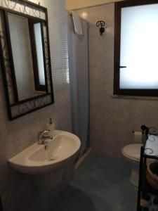 een badkamer met een wastafel, een toilet en een spiegel bij Villa Rossana in Scopello