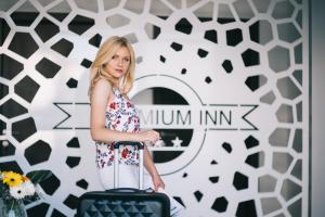a woman standing with a suitcase in front of a wall at Premium Inn in Gevgelija