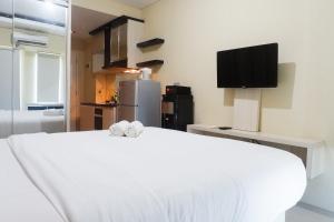 a bedroom with a white bed and a tv at Clean Studio Apartment Connected to Mall at Orchard Supermall Mansion By Travelio in Surabaya +6 photos