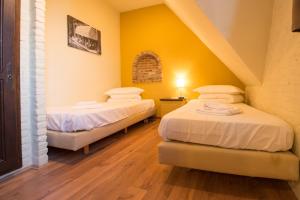 two beds in a room with yellow walls and wooden floors at City Flats by Lybeer Hotel Group in Bruges