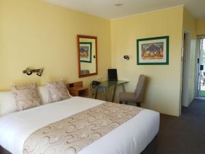 a bedroom with a bed and a desk with a computer at Moon River Motor Inn in Kempsey