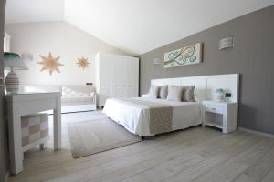 a bedroom with a white bed and a desk at Eliantos Boutique Hotel & Spa in Santa Margherita di Pula