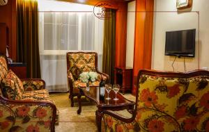 a living room with chairs and a table and a tv at Royal House Hotel in Ulaanbaatar