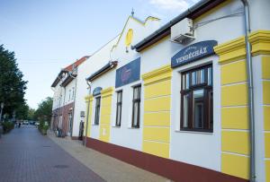 a row of yellow and white buildings on a street at Chicago Vendégház in Szentes