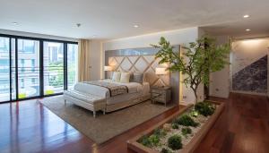 a bedroom with a large bed and a plant at Benviar Tonson Residence in Bangkok