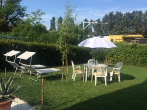 una mesa, sillas y una sombrilla en un patio en DEPENDANCE LAZISE LAGO DI GARDA en Lazise