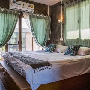 uma cama grande num quarto com cortinas verdes em Falik Farm Stay em Phra Nakhon Si Ayutthaya