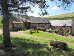 un edificio con un árbol y un parque con flores en Mill Of Nethermill Holidays, en Pennan