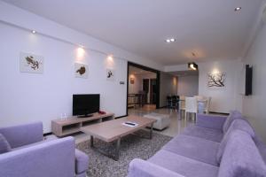 sala de estar con 2 sofás morados y TV en Likas Square - KK Apartment Suite en Kota Kinabalu