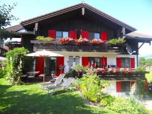 a house with red shutters and chairs in the yard at Ferienwohnungen Schmidbauer in Fischen