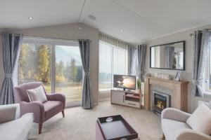 Platinum Holiday Caravan في Bothel: غرفة معيشة مع موقد وتلفزيون