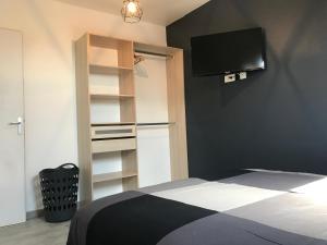 1 dormitorio con 1 cama y TV en la pared en Résidence Henri Dunant, en Valenciennes