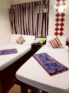 twee bedden in een kamer met twee tafels bij Simplex Guest House in Hong Kong