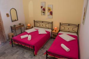 two beds in a room with red sheets and pillows at Golden Sun Rooms in Pyrgi Thermis +25 photos