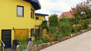 a yellow house with a garden next to a sidewalk at Geräumige in Jägerhof