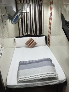 香港的住宿－天際賓館，一张白色的床,在房间里带条纹床头板