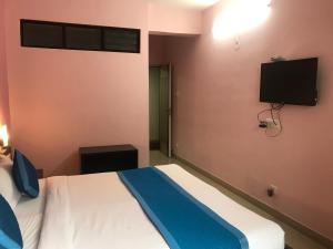 a bedroom with a bed and a tv on the wall at All Seasons Guest House I Rooms & Dorms in Madgaon