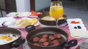 una mesa con dos sartenes de comida y un vaso de zumo de naranja en Saray Hotel, en Prizren