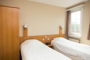 two beds in a room with a window at Hotel Bristol Internationaal in Mortsel