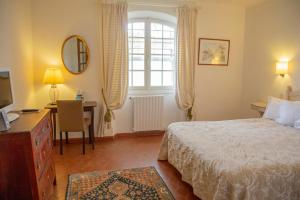 Schlafzimmer mit einem Bett, einem Schreibtisch und einem Fenster in der Unterkunft Hôtel Saint Andre in Saint-Tropez