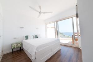 biała sypialnia z łóżkiem i dużym oknem w obiekcie Moonkey - Casa El Cabo w mieście Balcon del Mar