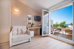 a living room with a white chair and a sliding glass door at Hotel Maritimo in Makarska