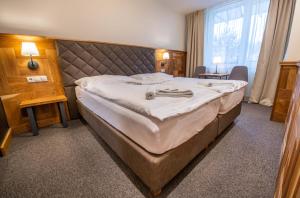 
a hotel room with a bed, chair, and nightstand at Hotel Čingov Slovenský raj in Smižany
