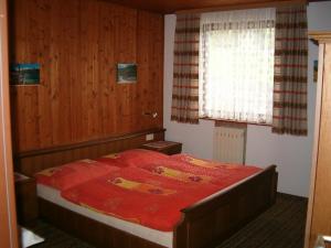 a bedroom with a bed with a red comforter and a window at Haus Erna in Rauris