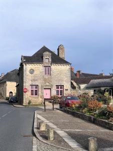 un vieux bâtiment en pierre avec une porte rose dans une rue dans l'établissement L'Ancienne Boulangerie, à Collinée