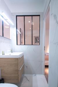 een witte badkamer met een wastafel en een raam bij Dreamyflat - Eiffel tower in Parijs