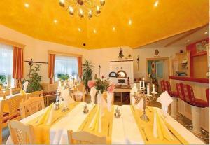 ein Esszimmer mit einem langen Tisch und einer gelben Decke in der Unterkunft Hotel Rosenberg in Jennersdorf