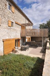a stone building with a patio with tables and chairs at Gites Domaine de Ceyrac in Conqueyrac