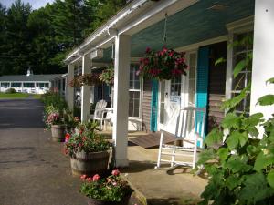 a porch of a house with potted plants and flowers at White Trellis Motel in North Conway
