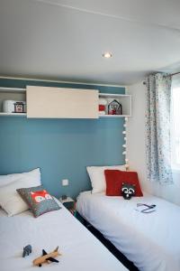 two beds in a bedroom with blue walls at Camping Les Sables Blancs in Concarneau