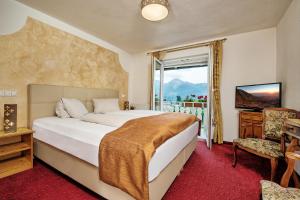 een slaapkamer met een groot bed en een raam bij Hotel-Pension Melcher in Drobollach am Faakersee