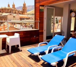 two blue chairs and a table on a balcony with a view at Hotel Xauen in Jaén