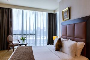 a hotel room with a bed and a large window at Kingsgate Hotel Doha by Millennium Hotels in Doha