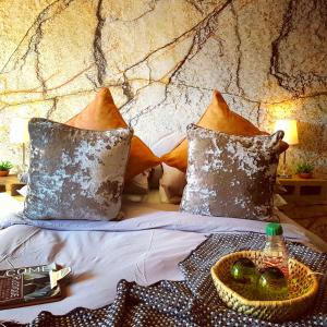 a bed with pillows and a table with a bottle on it at Rustique in Graskop