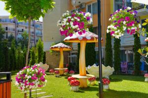 a garden with umbrellas and flowers in the grass at Sweet Homes Apartments in Sunny Beach