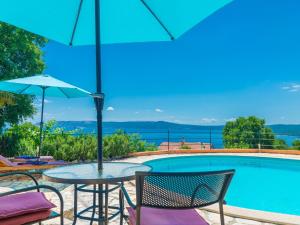 stół i krzesła z parasolem przy basenie w obiekcie Rural house for two with sea view w Crikvenicy
