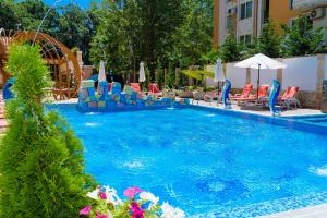a large swimming pool with chairs and umbrellas at Sweet Homes Apartments in Sunny Beach