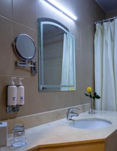 a bathroom sink with a mirror and a vase of flowers at Kingsgate Hotel Doha by Millennium Hotels in Doha