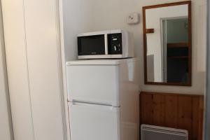 Un four micro-ondes est installé au-dessus d'un réfrigérateur. dans l'établissement Résidence Grand Bois A1118 Clés Blanches, à La Tania
