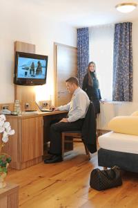 un hombre sentado en un escritorio en una habitación en Hotel Christl, en Rohrdorf
