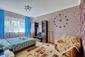 1 dormitorio con 1 cama y reloj en la pared en Apartment near the President's Park. Orbita-2 en Almaty