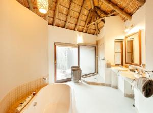 un ampio bagno con due lavandini e una vasca di Tambuti Lodge a Pilanesberg