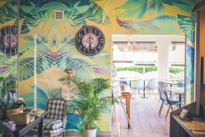 un restaurante con una pared colorida con un reloj. en Hôtel Le Plaisance, en Mimizan-Plage