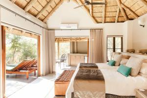a bedroom with a large bed and a living room at Tambuti Lodge in Pilanesberg