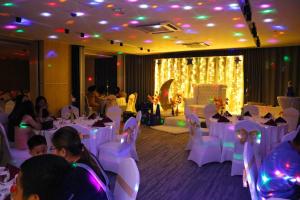 un salón de banquetes con mesas y sillas blancas y gente en Red Hotel Cubao, Quezon City, en Manila